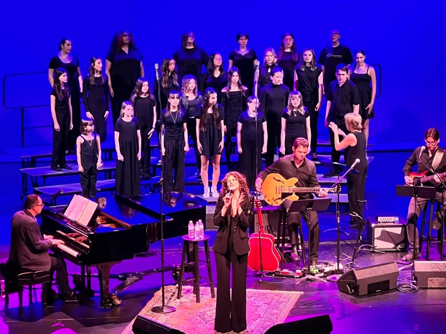 Flagler Performing Arts Academy choir and band performing on stage with blue lighting