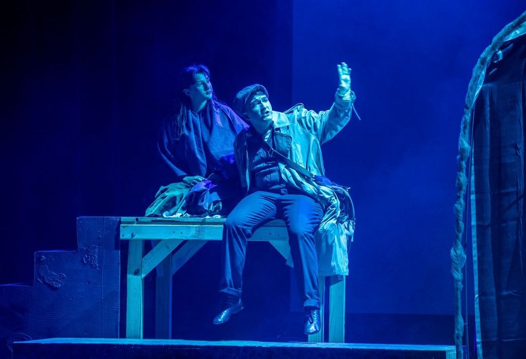 Two actors performing in blue stage lighting